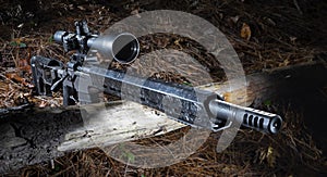 Bolt action rifle with riflescope on a log