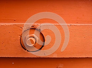 The bolt and nut are screwed into the wall of the house and painted with orange paint. The construction of a modern building.