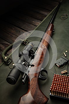 Bolt small caliber rifle 22lr with an optical sight on a wooden background. Hunting small-caliber weapon on a wooden table