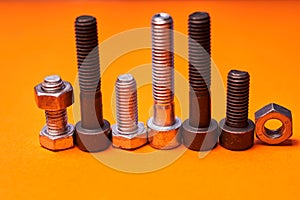 Bolted connecting elements on orange background close-up