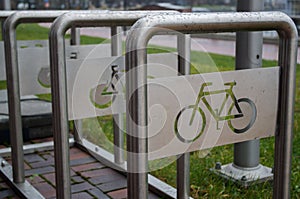 Bolted to pavement structure of series of metal arcs with plates in which image of bike is cut for parking and bicycles attachment