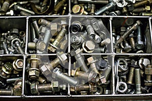 Bolts in an iron box. Screws, tools, nuts, metal.
