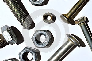 Bolts and nuts of different sizes lie on a white background. top view