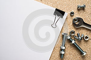 Bolts, nuts and paper blank on a chipboard table