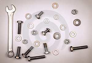 Bolts, nuts, washers and wrench on a gray background