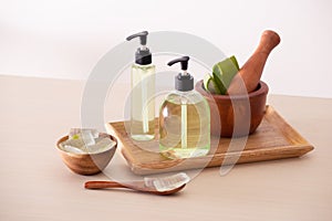 Bolw of aloe on cutting board and organic shower gel in bottle on wood tray