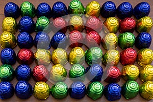 Bonbons in multicolored foil wraps in rows on table