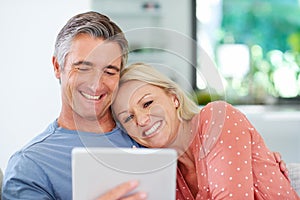 Bonding and browsing. a mature couple relaxing with their digital tablet at home.
