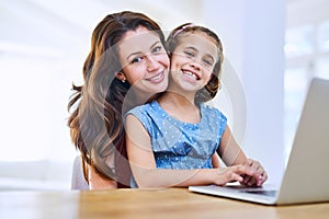 Bonding and browsing. Portrait of a mother and daughter using a laptop together at home.