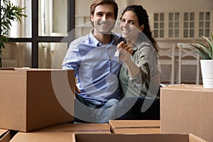 Bonding couple sit on couch holding keys celebrate moving day