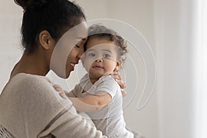 Bonding mixed race young mommy cuddling sweet little kid.