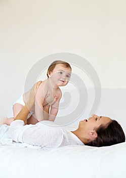 Bonding with my baby. A young mother lying on her back and holding up her baby girl while laughing.