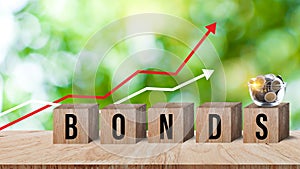 Bonds word in wooden blocks with coins stacked in increasing stacks. Bonds increasing concept, investment bond concept Raising