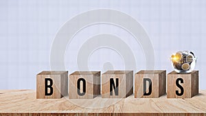 Bonds word in wooden blocks with coins stacked in increasing stacks. Bonds increasing concept, investment bond concept Raising