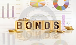 Bonds the word on wooden cubes, cubes stand on a reflective surface, in the background is a business diagram