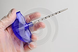 Bone marrow biopsy needle held in doctor left hand in glove.