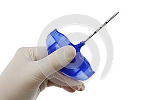 Bone marrow biopsy needle held in palm of doctor left hand in powdered latex glove, white background