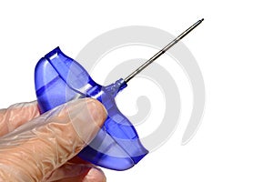 Bone marrow piopsy needle held in left hand of a doctor in latex sterile glove, white background