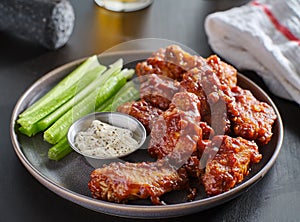 Boneless chicken wings covered in honey garlic bbq sauce with ranch and celery