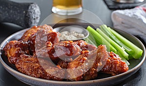 Boneless chicken wings covered in honey garlic bbq sauce with ranch and celery