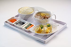 Boneless Hainanese Chicken Rice with chicken soup, soy sauce, chili sauce served in bowl isolated on wooden table side view of