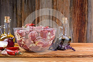 Boneless lamb steak, sliced and marinated with onions, meat in a glass bowl, Basil, chili pepper, marinades on a wooden