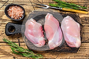 Boneless Raw Chicken thigh fillet. Wooden background. Top view