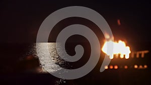 Bonfire on background sea which moon reflected night camping seashore