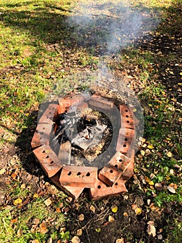 Bonfire in a clearing in the garden, fenced with bricks for fire safety.