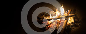 Bonfire, log fire, or campfire in dark background with flame, burned log wood, firewood in home fireplace for heating or camping