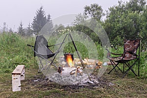 Bonfire in nature. the kettle is warming in the flame. Cozy outdoor camping in a clearing in the forest