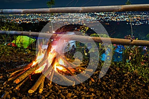bonfire and some sparks on the camping ground, with citylight in the background