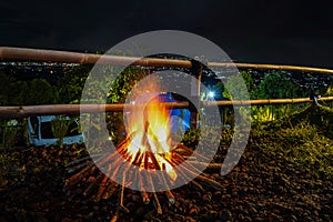 bonfire and some sparks on the camping ground, with citylight in the background