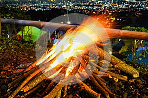 bonfire and some sparks on the camping ground, with citylight in the background