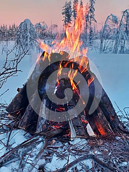 Bonfire in Swedish winter landscape at dusk