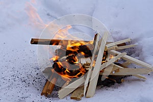 Bonfire on the white snow in winter, fire and chips