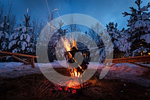 Bonfire in the winter forest illuminates the snow