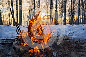 Bonfire winter in the forest at sunset .