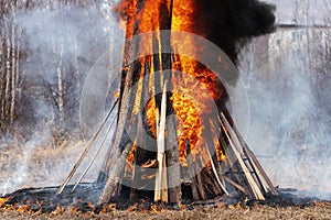 Bonfire of wooden boards and car tires, flame of red fire, curling black smoke