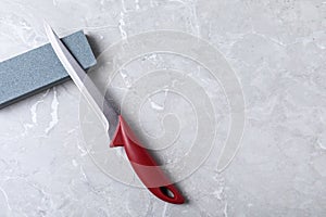 Boning knife, sharpening stone on grey background, flat lay
