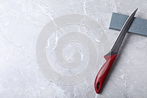 Boning knife, sharpening stone and space for text on grey background