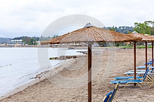 Bonita umbrella piling up in the beach. Portable lazy chairs diplay under the hut and facing the shoreline . resort amenities for