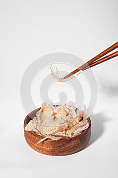 Bonito flakes in a bowl on white background. Katsuobushi is dried, fermented and smoked skipjack tuna fish