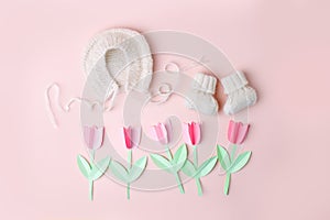 Bonnet and booties on a pink background. Handmade clothes for a newborn, decorative paper flowers. Newborn baby gift concept, mom