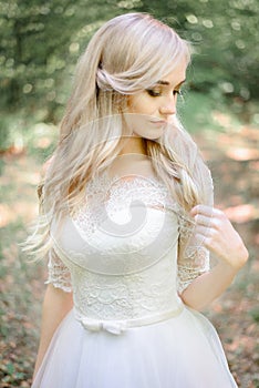 Bonny blonde bride touches her hair delicately