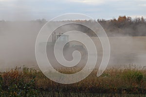 BONNYVILLE, ALBERTA, CANADA - SEPTEMBER 10, 2020: A local farmer in John Deere tractor works in a cloud of dust as he