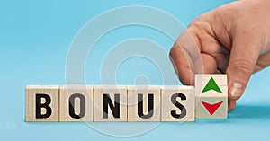 Bonus is going up or vice down. Hand is turning wooden cubes a dice and changes the direction of an arrow symbolizing