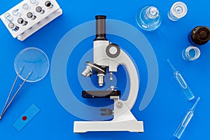 Bood testing with microscope in laboratory. Equipment on blue background top view