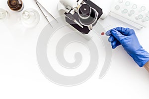 Bood testing with microscope in laboratory. Sample in hands on white background top view copy space photo