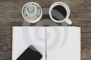 Book, cactus and coffee cup placed on a wooden table